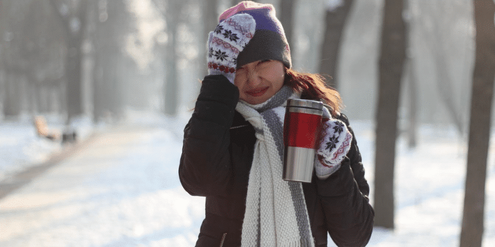 woman cold outside wind blowing drinking hot coffee stainless steel