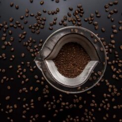 Reusable Pour Over Coffee Filter: Stainless steel mesh filter with ground coffee, surrounded by roasted beans