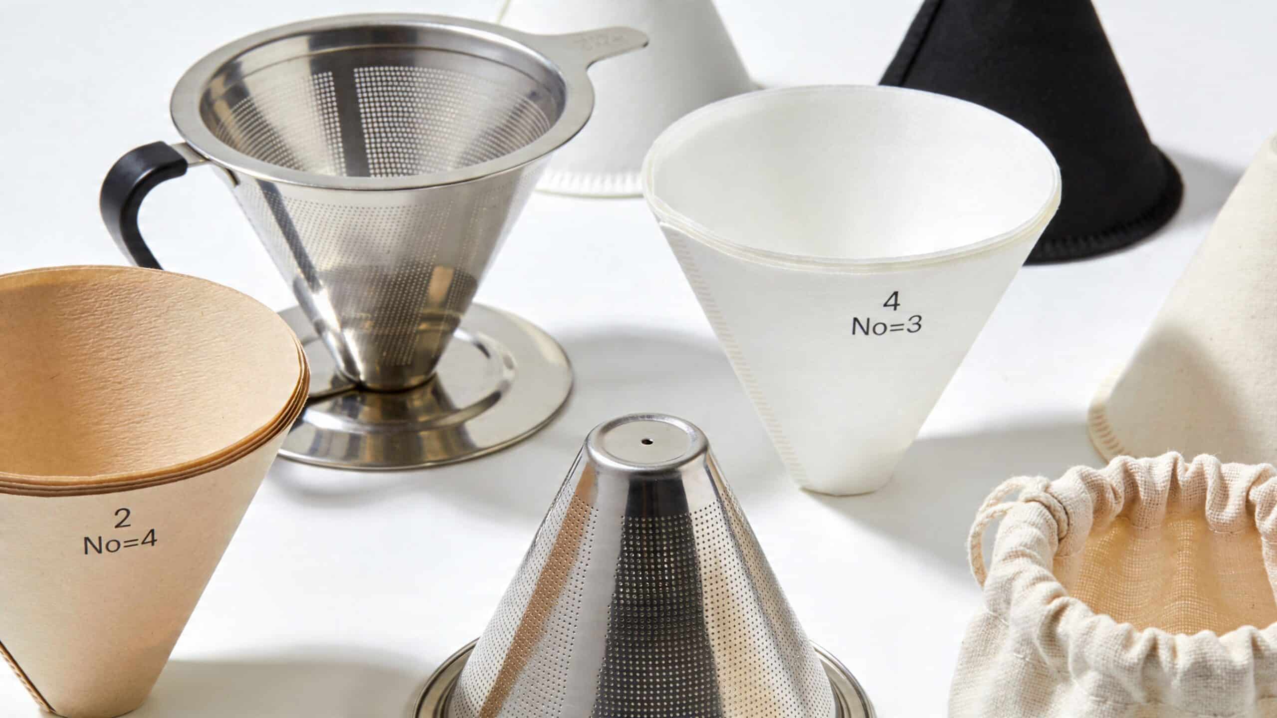 A collection of various metal, paper, and fabric cone filters for brewing pour-over coffee.