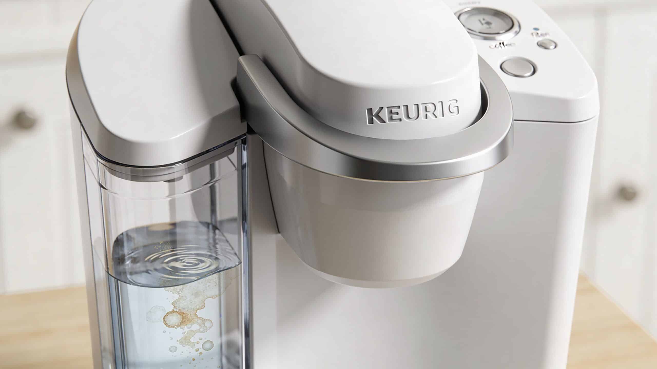 A clean white Keurig coffee maker machine sitting on a wooden kitchen countertop surface.