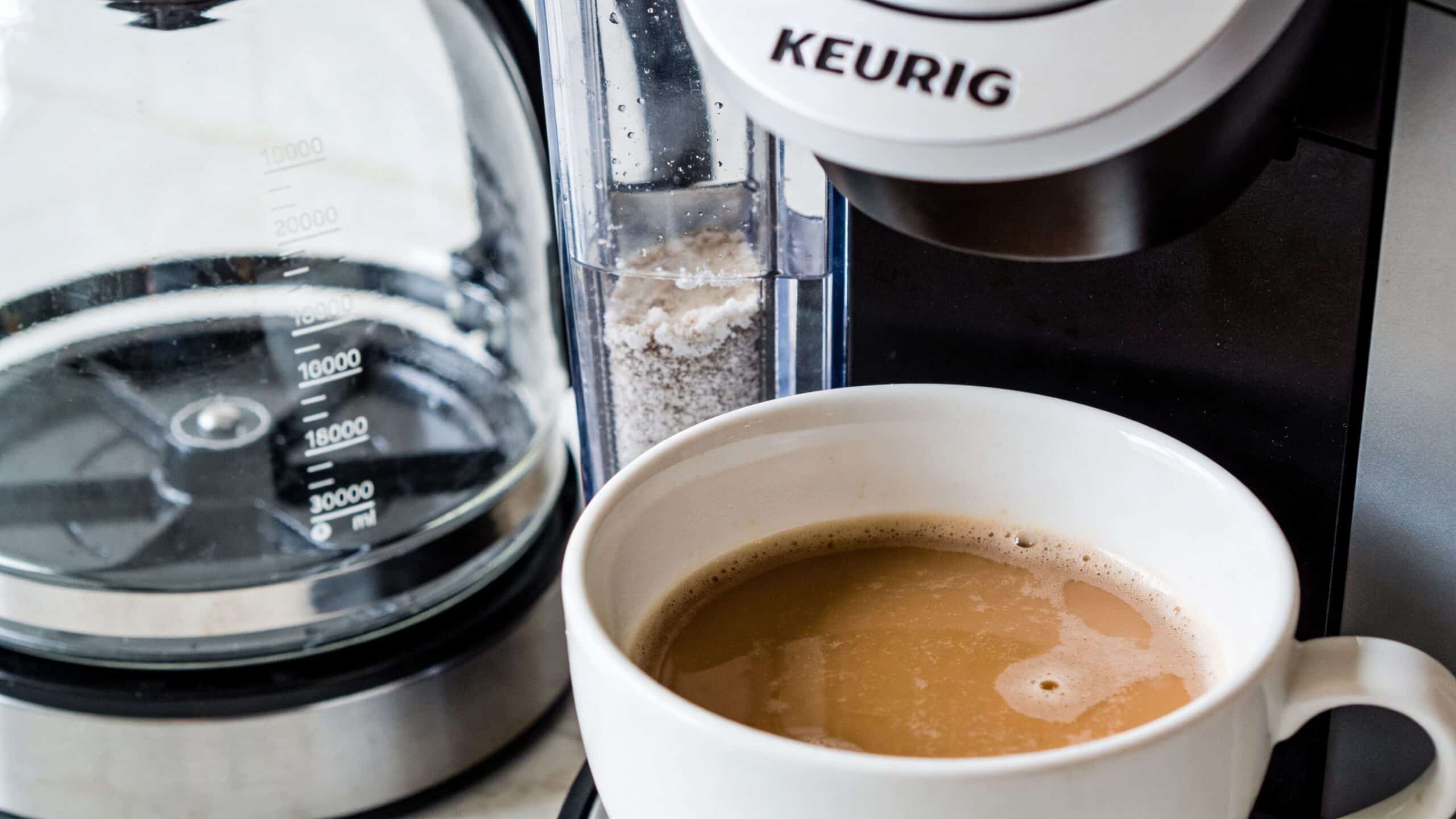 A close-up view of a Keurig coffee machine brewing coffee into a white mug with a water filter