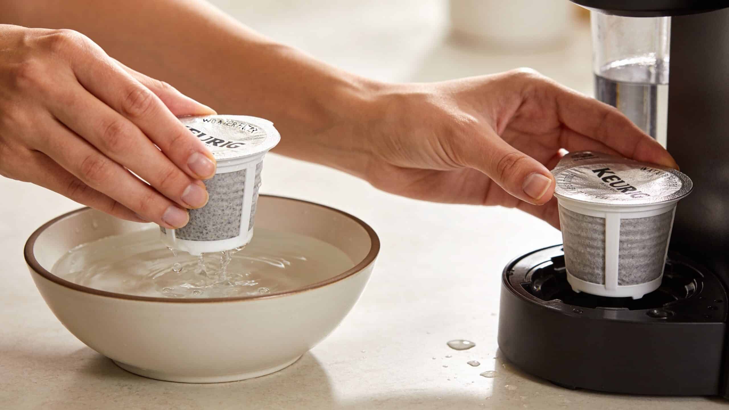A person soaking a Keurig water filter in a bowl before installing it into a coffee machine.