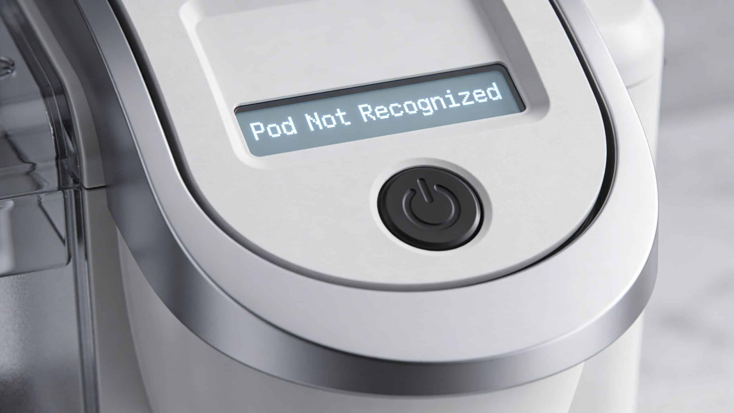 A close-up of a coffee machine control panel displaying a Pod Not Recognized error message on screen.