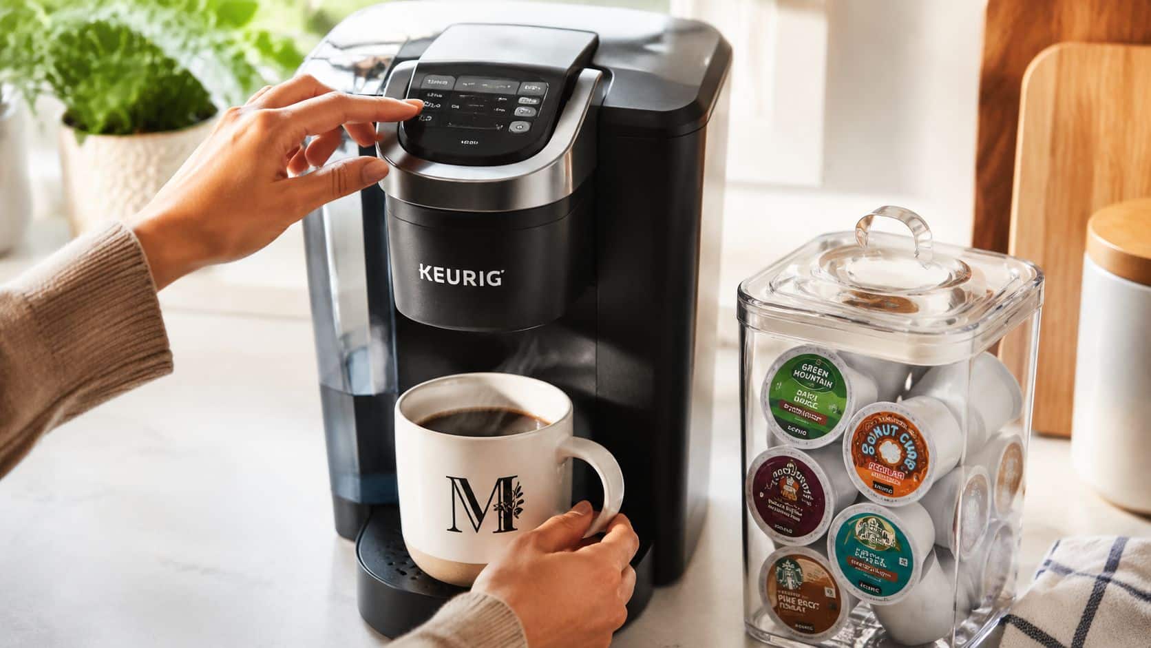 A person brewing coffee using a black Keurig machine with a variety pack of K-Cup coffee pods nearby.