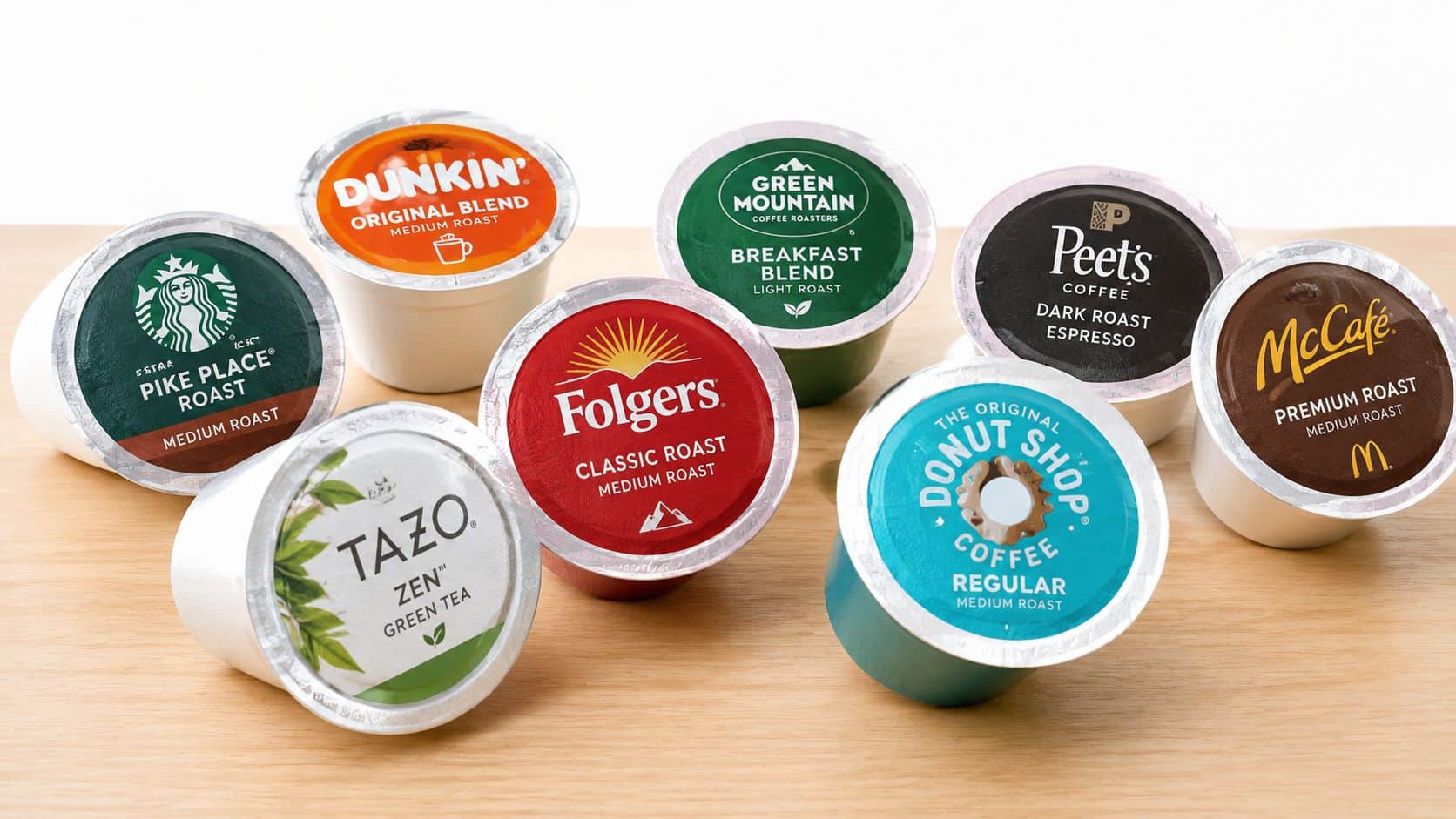 A collection of various popular branded coffee and tea K-Cup pods arranged on a wooden surface.