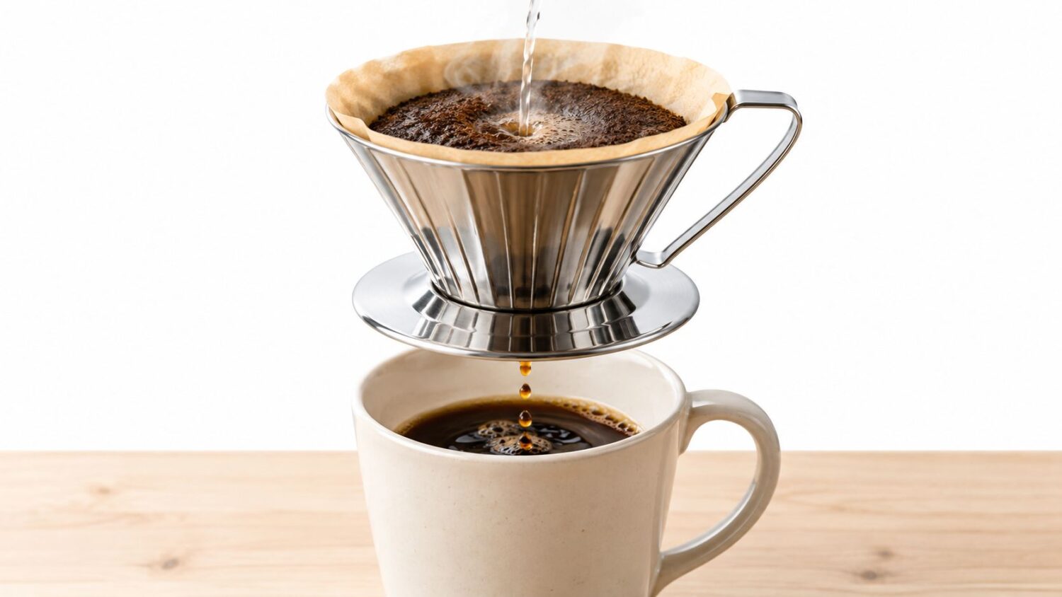 Pouring hot water over coffee grounds in a pour-over coffee maker, dripping into a mug.