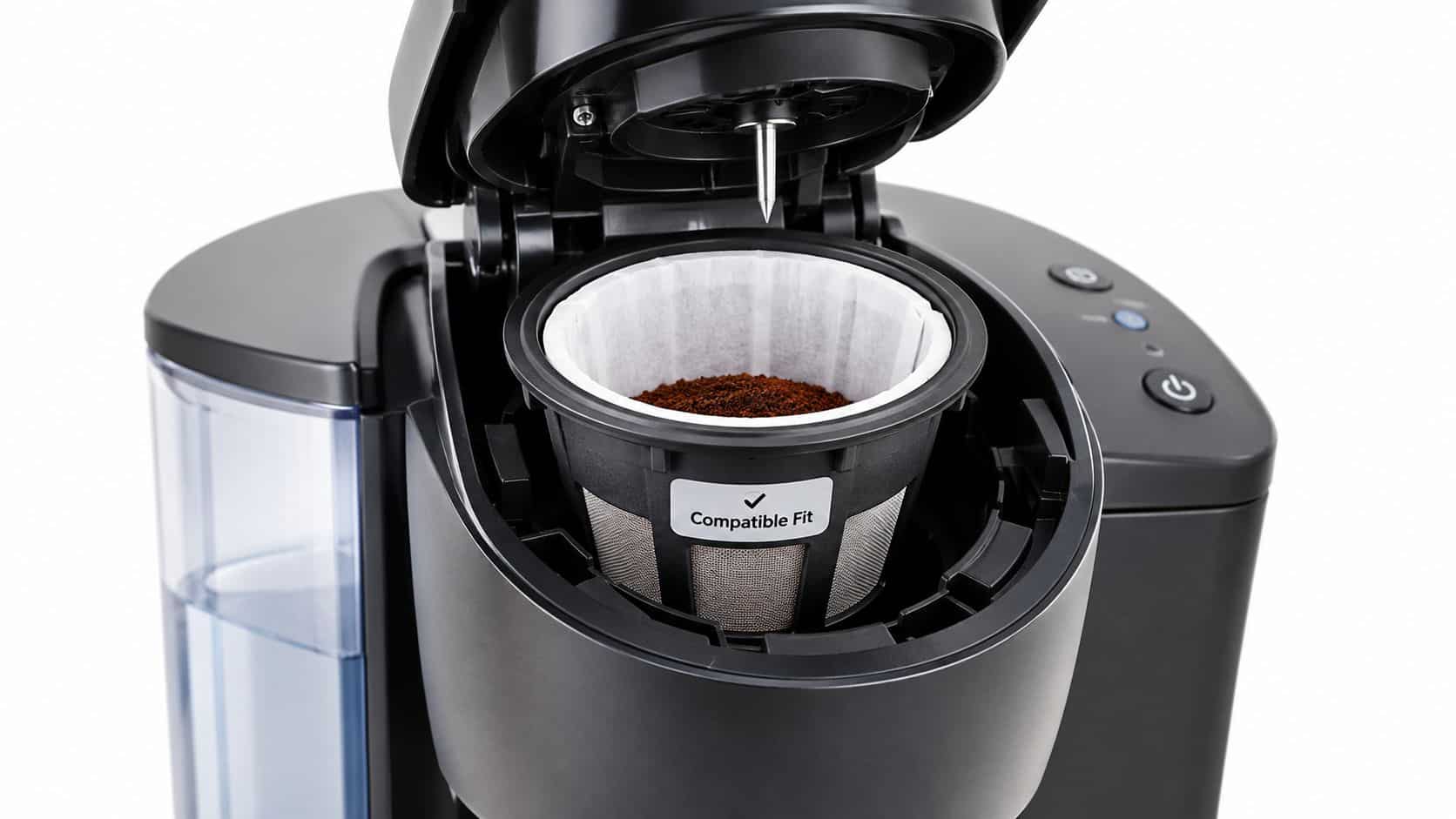 A close-up view of a single-serve coffee maker with a reusable filter cup containing coffee grounds.