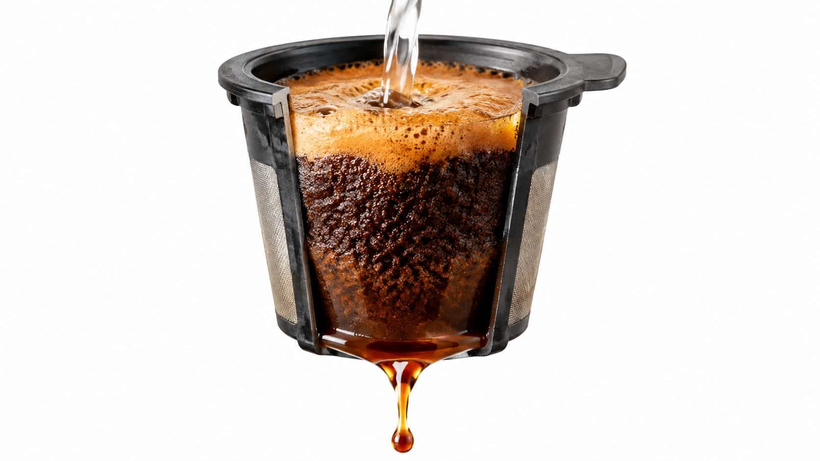 A cross section of a reusable K-cup coffee filter being filled with hot water and brewing espresso.